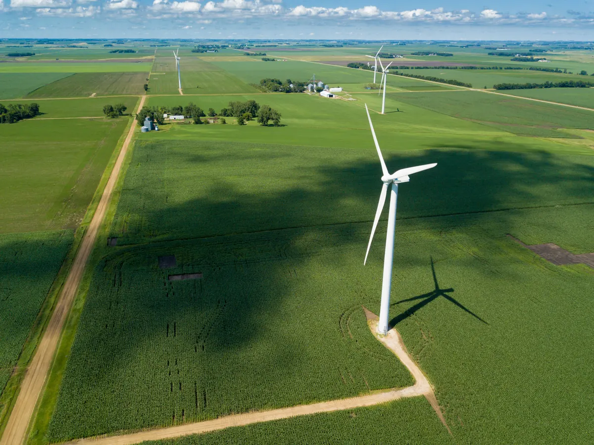 Aerial view of farm fields with a wind turbine