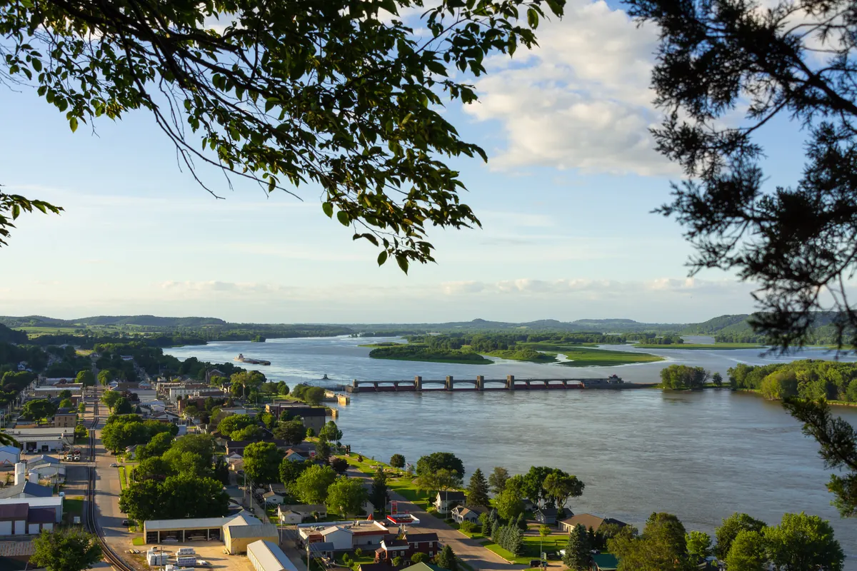 Mississippi River valley seen from a bluff top, with a river town and bridge below