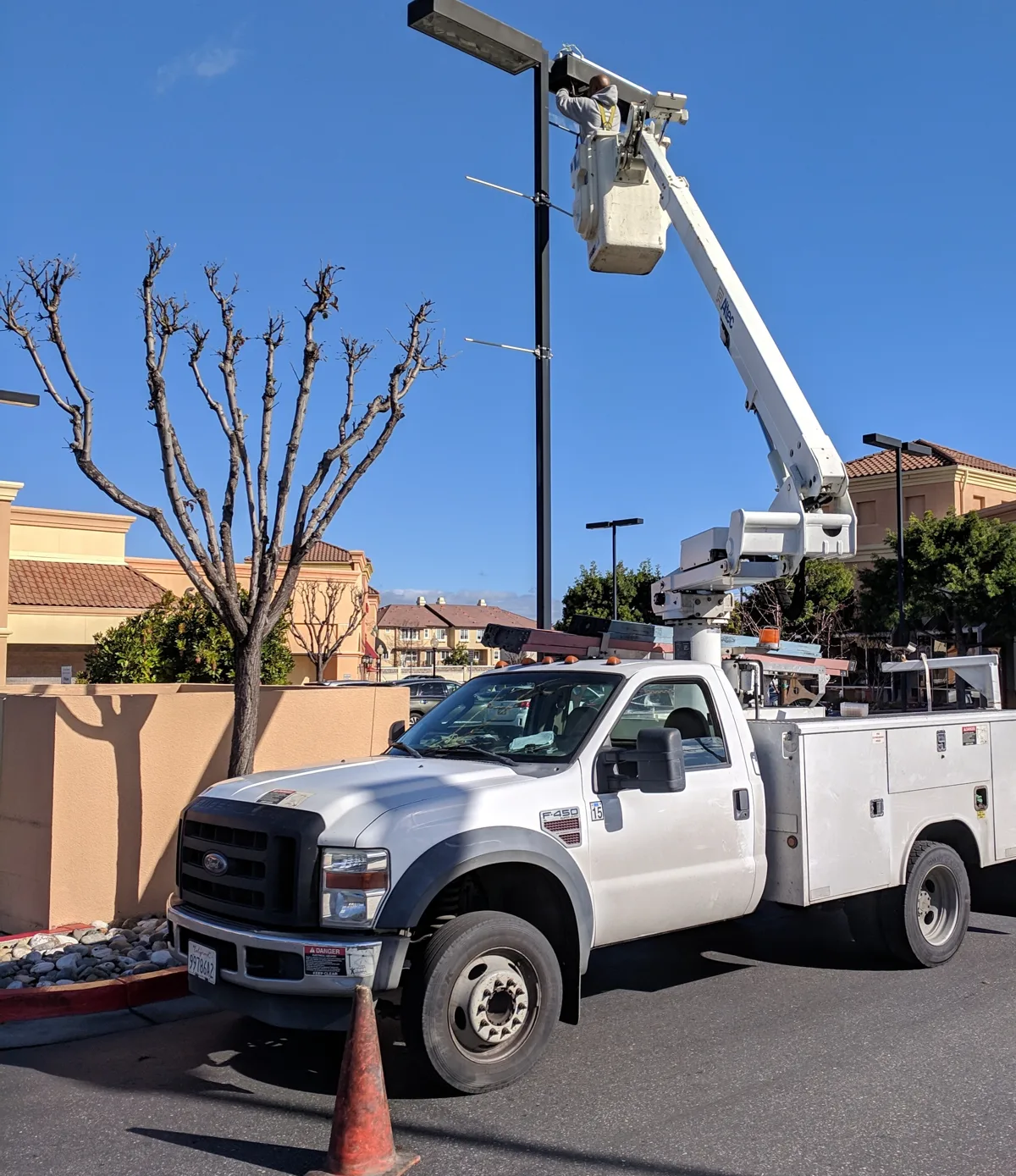 Electrician in a bucket truck servicing a parking lot pole light