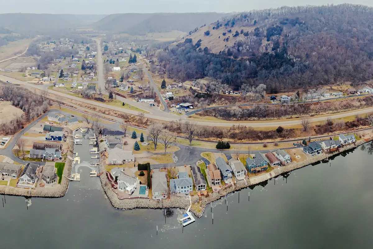Aerial view of Brownsville, Minnesota, with riverfront homes and a large wooded bluff above the town.