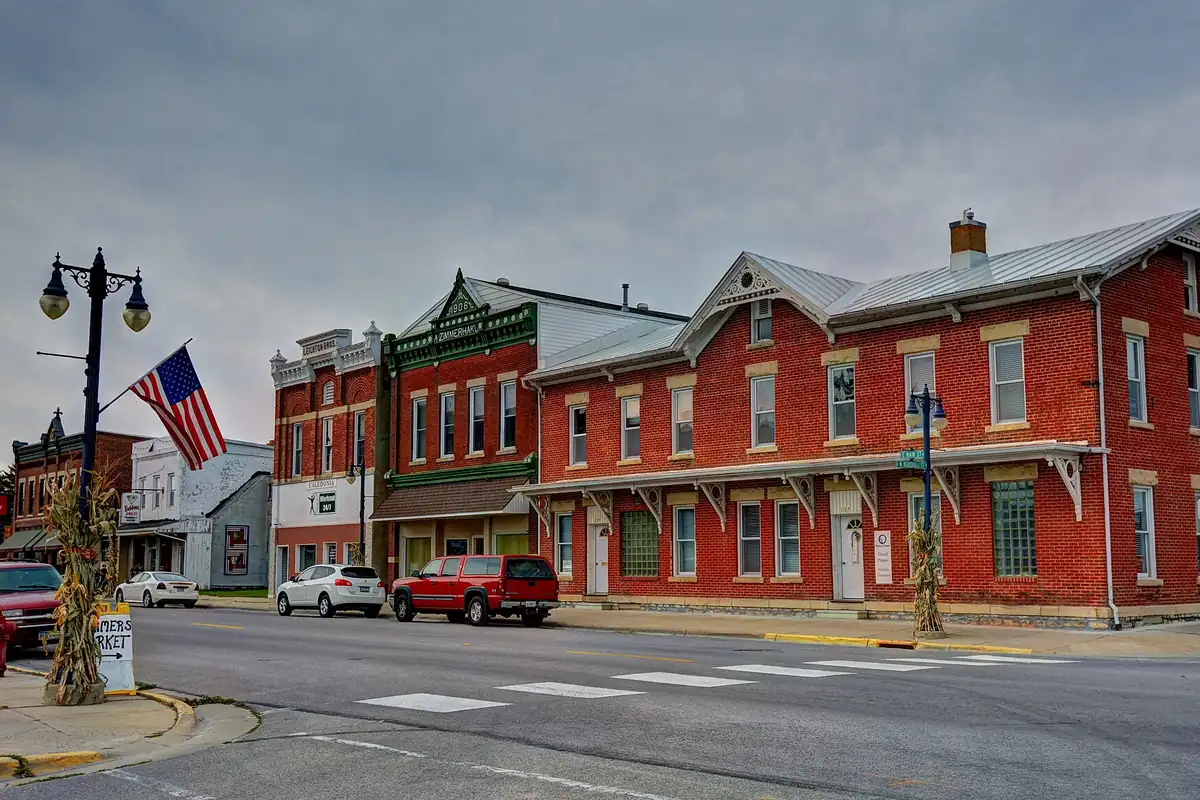 Historic brick storefronts on the main street of Caledonia, Minnesota, with a flag and street lamps.