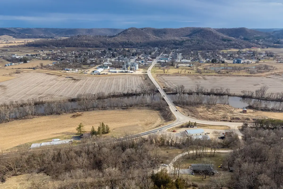 Aerial view of Houston, Minnesota, across the river and fields with bluffs behind the town.