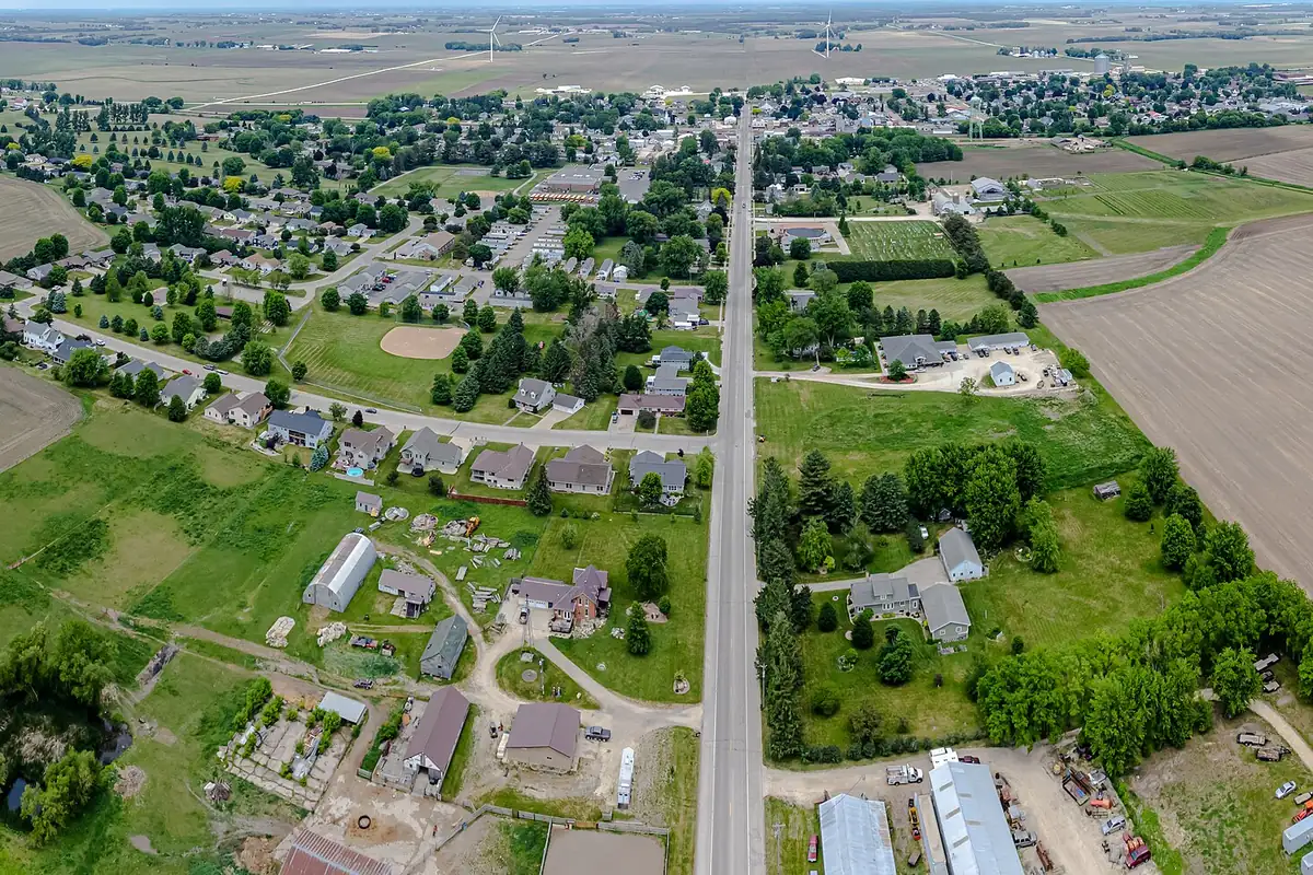 Aerial view of Lewiston, Minnesota, with tree-lined streets and homes along a main road surrounded by farm fields.